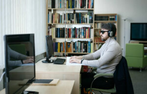 man with sunglasses and headphones sitting at a computer