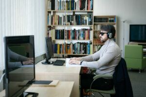 man with sunglasses and headphones sitting at a computer